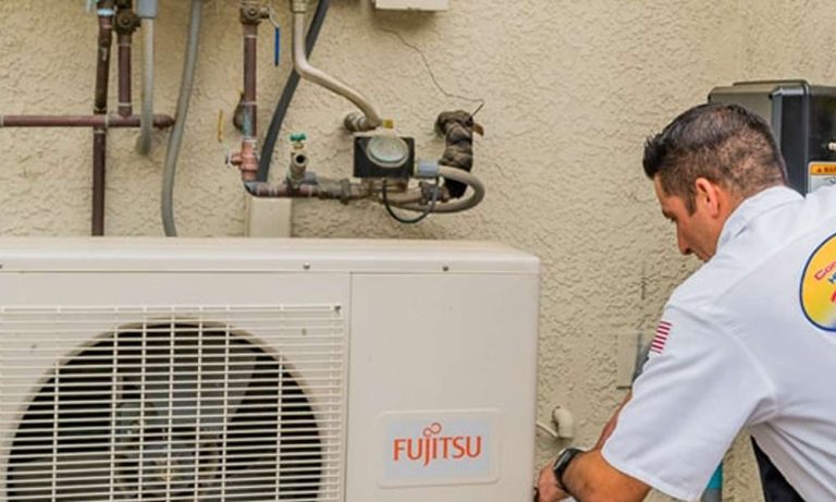 Technician servicing Fujitsu air conditioning unit. HVAC repair.