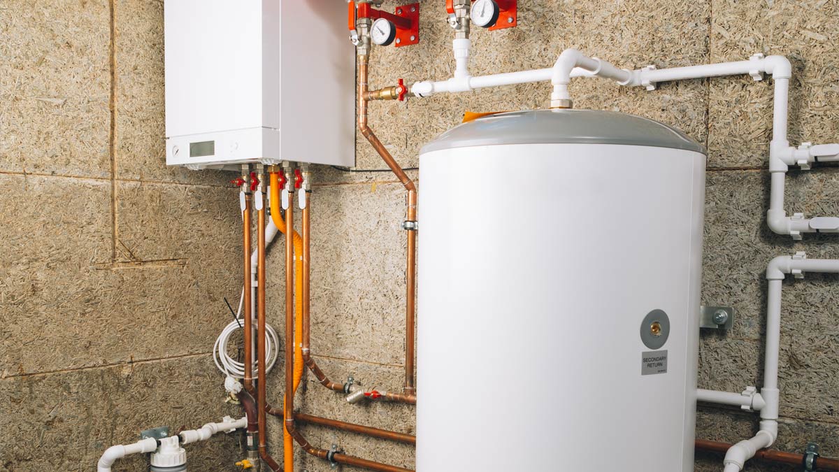 Copper pipes and valves connect a combi boiler and hot water tank.
