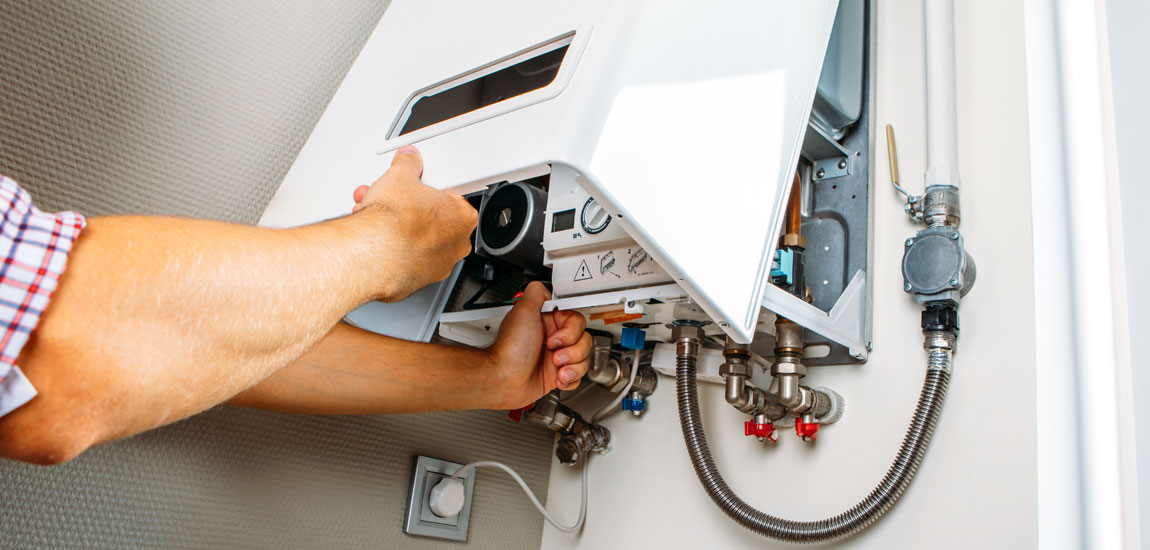 Technician repairing a gas boiler, inspecting internal components and plumbing.