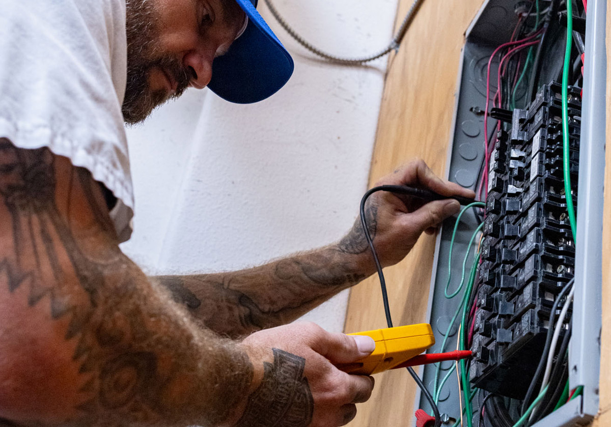 Electrician testing electrical panel with a multimeter