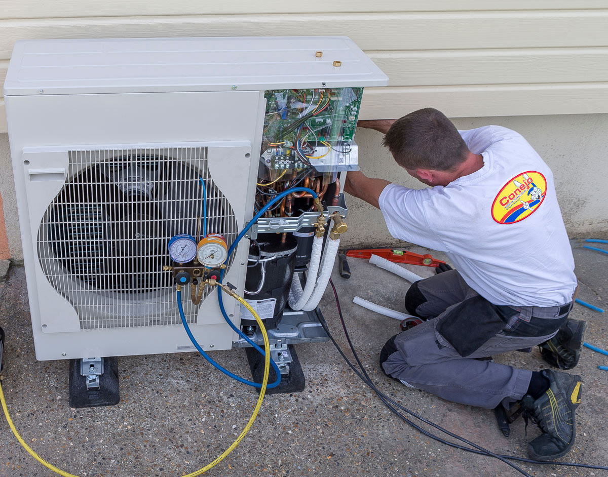 Technician servicing an air conditioning unit outdoors.