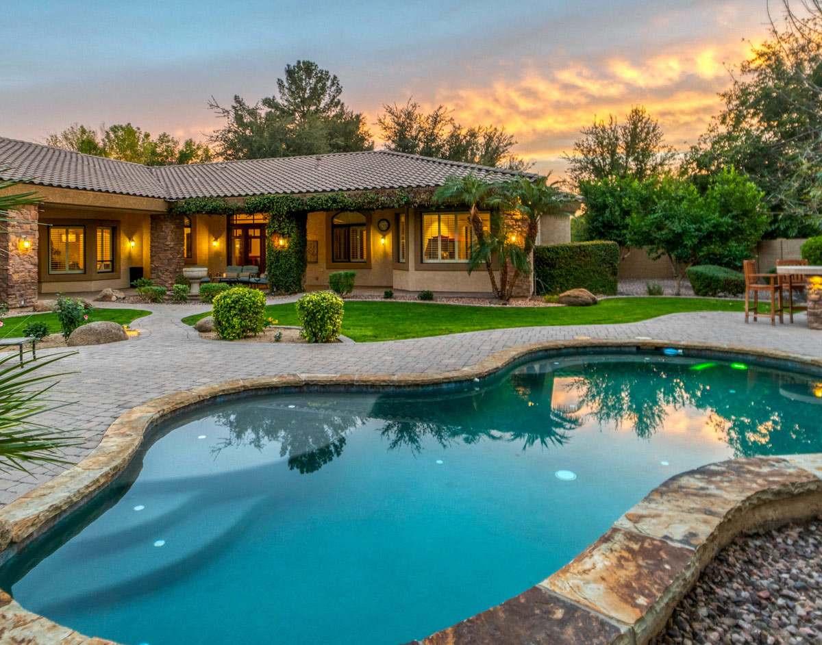 Luxury home with a freeform pool at sunset. Arizona real estate.
