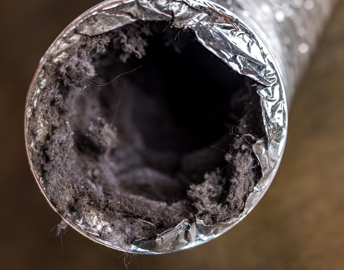 Close-up of a dryer vent clogged with lint and debris.