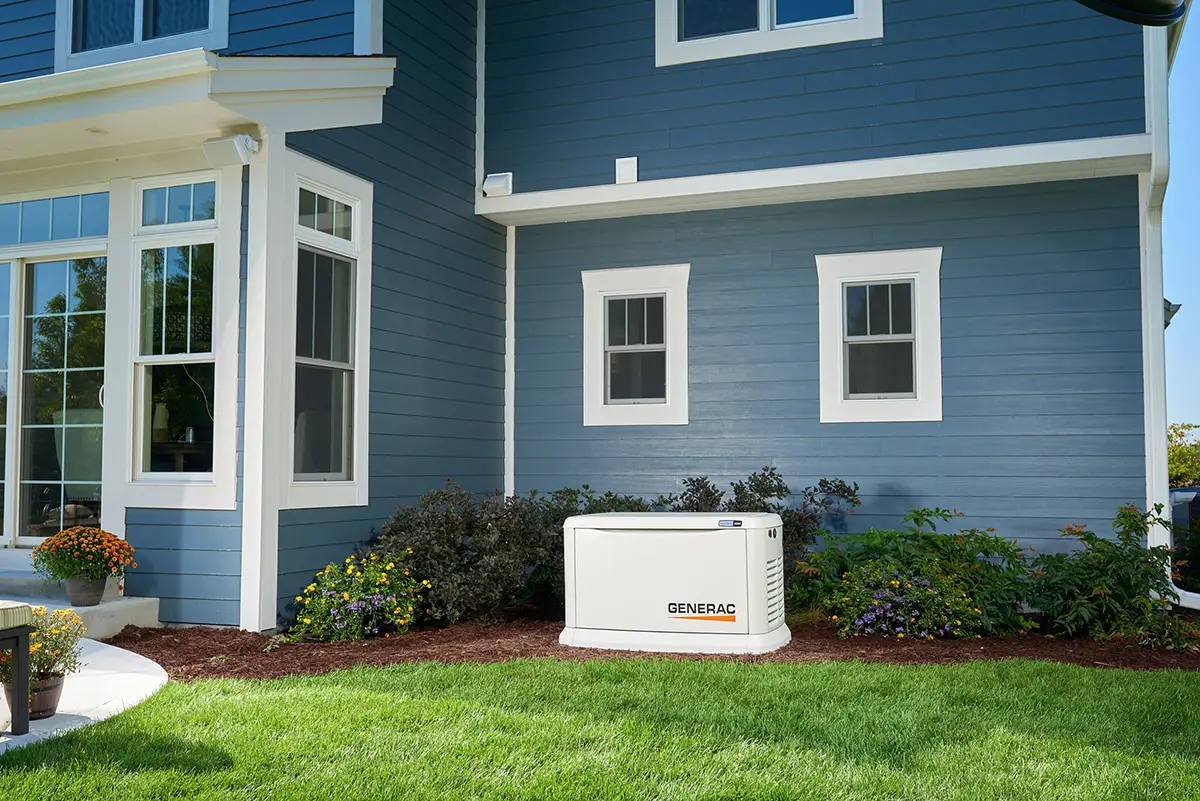 Generac home standby generator installed outside a blue house.